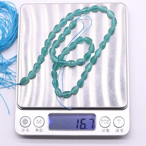 Macro shot of turquoise teardrop faceted beads on scale weighing 16.7g for DIY jewelry