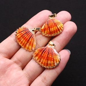 Détails de pendentifs en coquillage naturel avec bords dorés tenus à la main