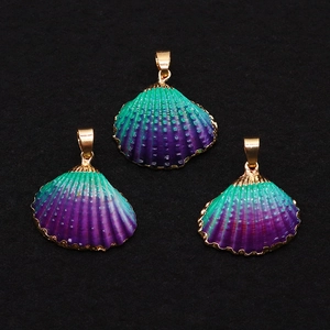 Macro view of gradient green and purple scallop shell pendants with gold plated edges