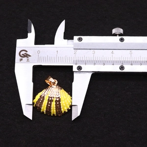Detail showing shell pendant width measurement with caliper on black velvet