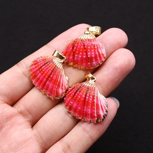 Gros plan sur trois pendentifs en coquillage doré avec une texture dégradée rose