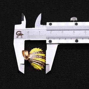 Detail view of a 20mm gold-edged shell pendant being measured with a digital caliper