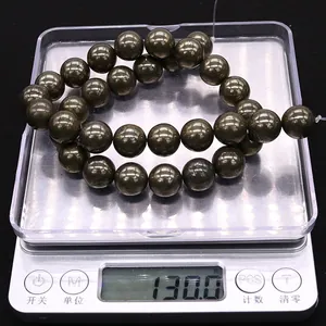 Macro detail of natural chalcopyrite stone beads on digital scale weighing 130 grams