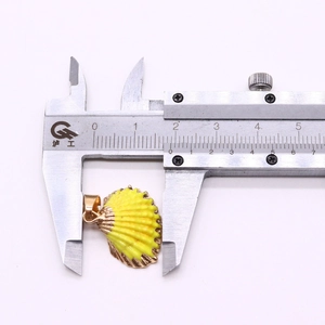 Detailed measurement of gold-plated shell pendant showing 20mm width on a caliper