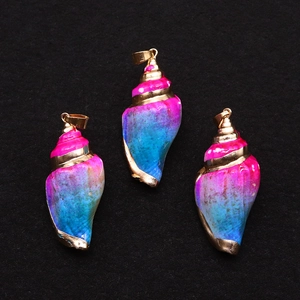 Detalle de tres colgantes de concha galvanizados con degradado rosa y azul sobre fondo negro