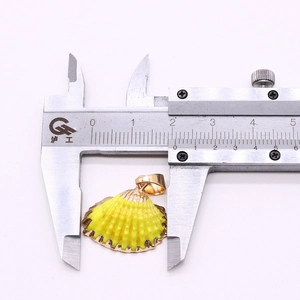 Calper tool measuring 18.5mm width of a natural yellow shell pendant with gold edging