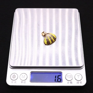Close-up of a gold-plated shell pendant weighing 1.6 grams on a digital scale