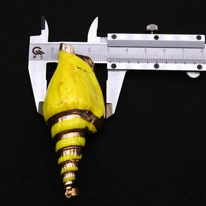 Macro shot measuring 2.8cm width of yellow conch shell pendant with gold plated edges