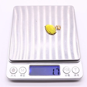 Macro shot of a yellow shell pendant with gold plating on a scale weighing 1.7 grams