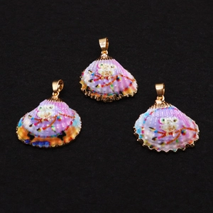 Détail macro de trois pendentifs en coquillage doré avec motifs de chouette sur fond noir