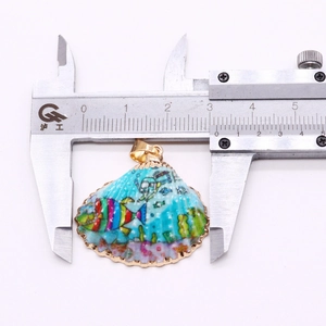 Mesure de la largeur du pendentif en coquillage naturel avec un pied à coulisse