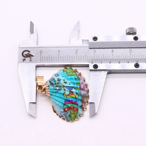 Vue détaillée de la mesure de 3cm d'un pendentif coquillage peint avec bordure dorée