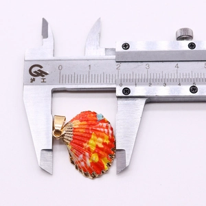 Vue macro mesurant la largeur de 19mm du pendentif coquillage avec un pied à coulisse