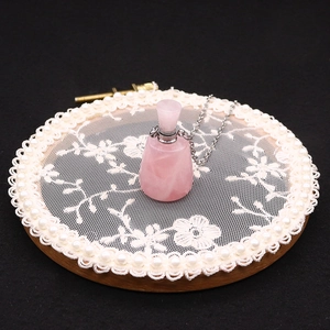Macro shot of rose quartz essential oil bottle pendant with delicate silver chain