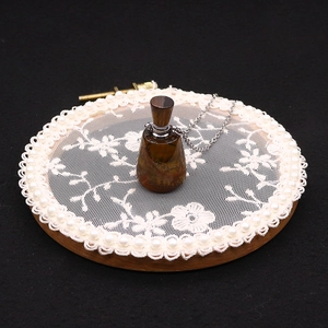 Tiger eye stone essential oil bottle necklace on a decorative lace background