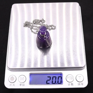 Makroansicht lila Amethyst-Parfümflaschen-Anhänger mit 20g Gewicht auf einer Waage