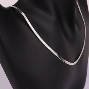Detailed close-up of a silver flat snake chain necklace on a black matte model