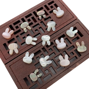 Natural rabbit-shaped shell beads in assorted colors displayed on vintage wooden trays