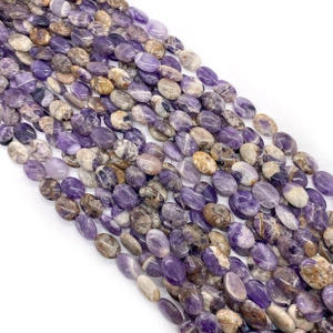 Macro shot of polished oval dog tooth amethyst beads with purple marble texture