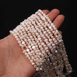 Natural freshwater baroque pearls being held in hand with a high gloss finish on black background