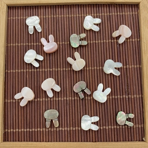 Macro shot of rabbit-shaped natural shell beads in white and grey on a bamboo mat background