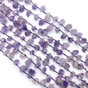 Detail of purple natural raw stone beads with black hand-knotted cord for DIY jewelry