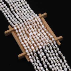 Strands of white freshwater pearls with natural luster on a bamboo display stand