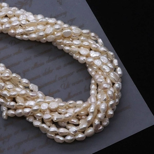 Strands of white baroque freshwater pearls with high luster on a dark elegant background
