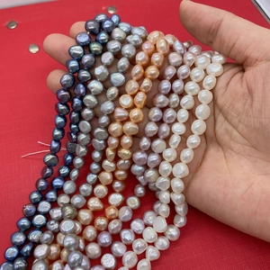 Macro shot of assorted baroque pearls in mixed colors held by hand for DIY jewelry making