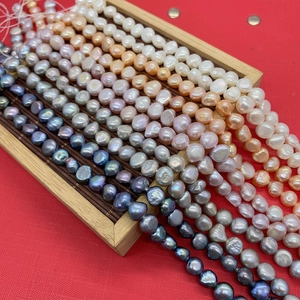 Macro detail of various baroque natural freshwater pearl strands in mixed colors on a wooden tray