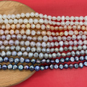 Macro shot of Grade A freshwater pearls in mixed colors on red textured fabric background