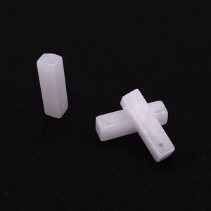 Detalle macro de tres colgantes rectangulares de piedra de ónice blanco con orificios