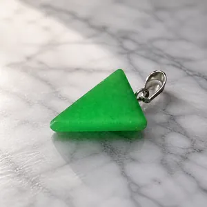 Foto macro de un colgante de piedra verde triangular de 2,32g en una báscula digital