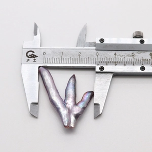 Macro view measuring a purple baroque pearl with calipers showing the unique claw shape