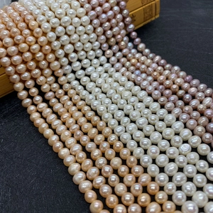 Macro detail of multi-colored natural freshwater pearls on a black textured surface