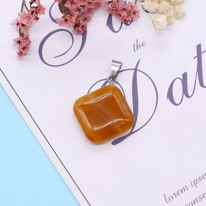 Amber-colored square stone pendant with silver bail shown on elegant decorative card
