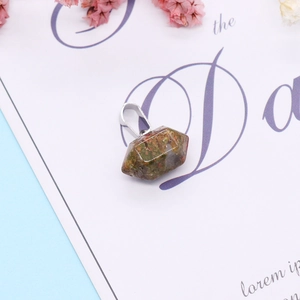 Macro shot of natural unakite stone pendant showing green and pink mineral texture