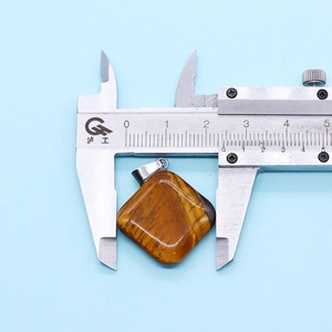 Measuring tiger eye stone pendant width of 25mm using a professional caliper tool