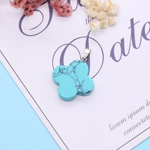 Gros plan d'un pendentif trèfle turquoise avec veines noires naturelles et fermoir argenté