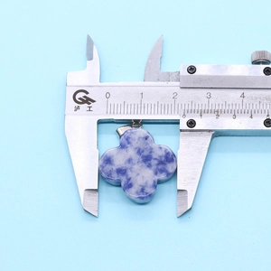 Macro detail of natural stone four-leaf clover pendant measured with a caliper