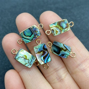 Set of five rectangular abalone shell connectors in gold metal frames held in hand