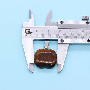 Detail shot of tiger eye apple pendant measuring 26mm width with a digital caliper
