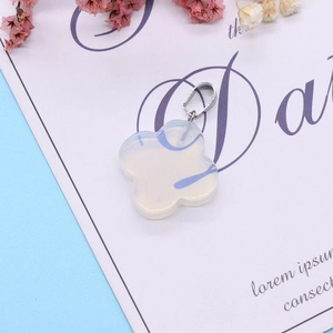 White opal four-leaf flower pendant with silver bail on a soft pastel background