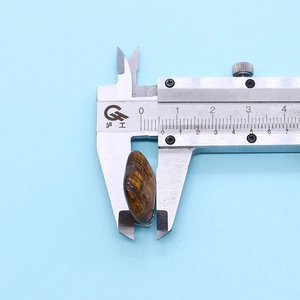 Macro shot of a 8.8mm tiger eye stone pendant measured by a silver vernier caliper