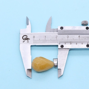Detail showing faceted yellow teardrop stone pendant measured with a caliper