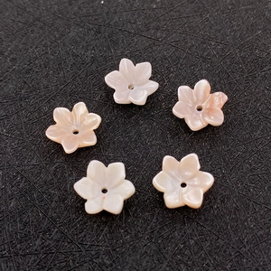 Detail van vijf bloemvormige natuurlijke schelphangers met middengat voor DIY-sieraden
