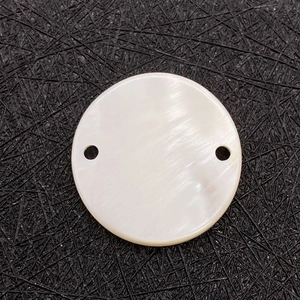 Macro view of polished white shell round connector with dual holes for DIY jewelry