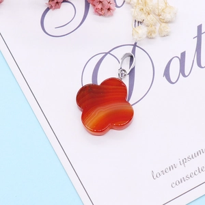 Macro shot of a four-leaf clover pendant made of natural red striped agate gemstone