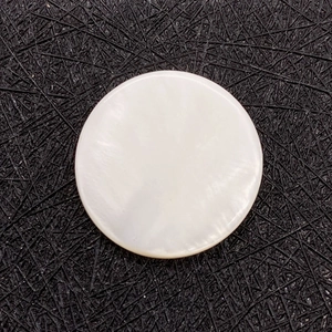 Macro detail of round white natural shell pendant showing iridescent mother of pearl texture