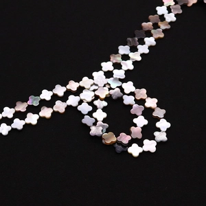 Détail macro de perles de nacre naturelle en forme de trèfle aux reflets irisés et texture